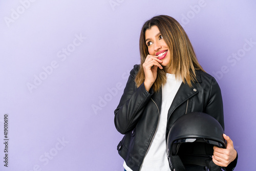Young indian motorbiker woman isolated relaxed thinking about something looking at a copy space.