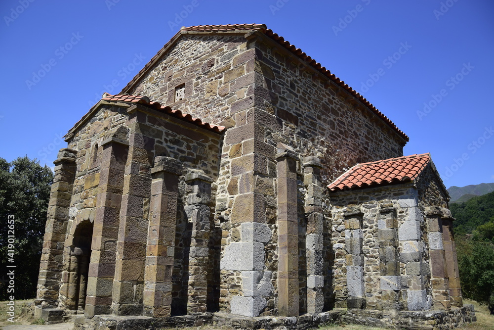 Vista lateral de una iglesia católica perteneciente al estilo prerrománico asturiano, con mil doscientos años de antiguedad y situada en medio de las montañas cubiertas de bosques del norte de España