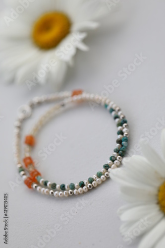 Bracelet of natural stones . Gemstone jewelry . Carnelian , crysocolla , pearls and citrine . Handmade jewerly on a white background with chamomiles. photo