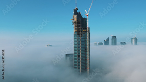 Astonishing aerial view of top of the Varso Tower under construction rising above clouds. High quality photo