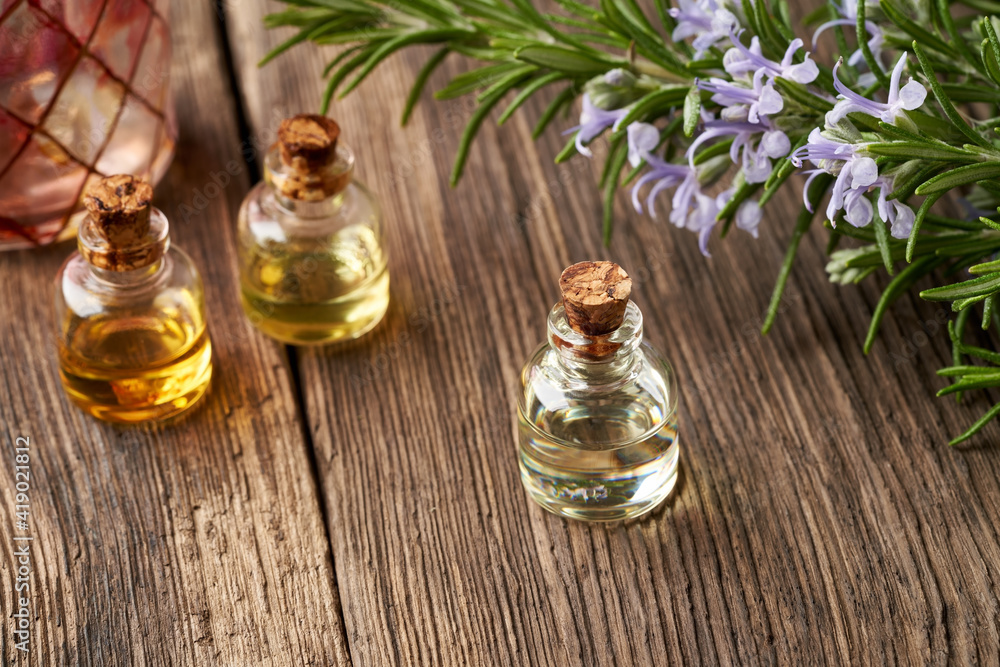 Essential oil bottles with fresh blooming rosemary twigs Essential oil bottles with fresh blooming rosemary twigs