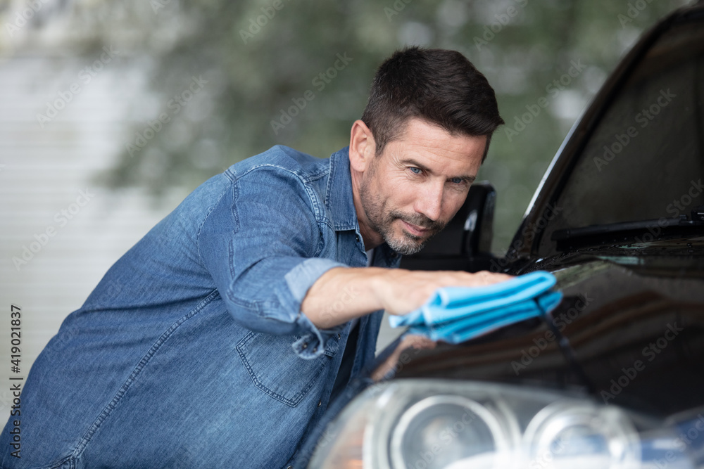 handsome man is washing car outdoor