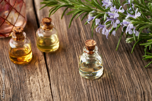 Essential oil bottles with fresh blooming rosemary twigs