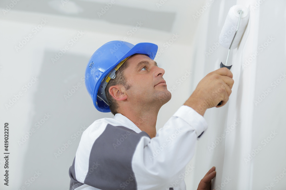 decorator painting a wall with a roller decorator painting a wall with a roller