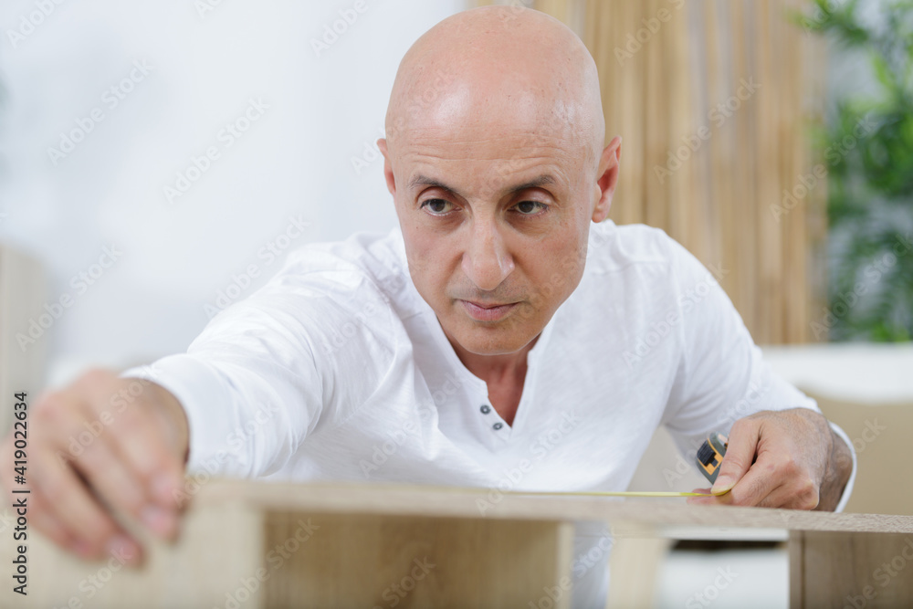 man using tape measure for measuring wooden kitchen counter man using tape measure for measuring wooden kitchen counter