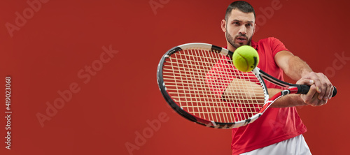 Website header of Seriously strong athlete male in red shirt playing tennis isolated on red background © Friends Stock