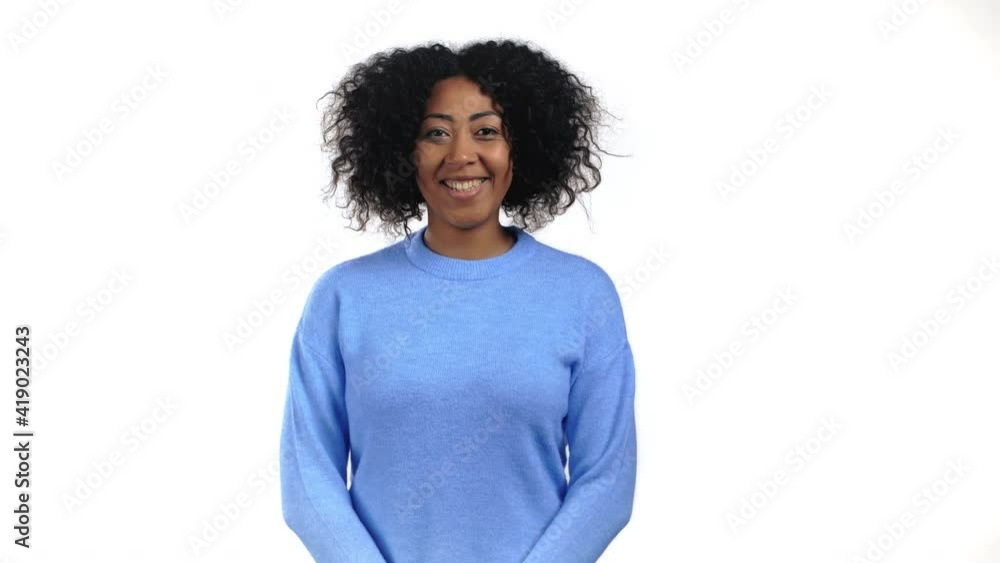African woman with curly hair looking to camera, smiling. Beautiful model girl in blue sweater on white studio background. African woman with curly hair looking to camera, smiling. Beautiful model girl in blue sweater on white studio background.