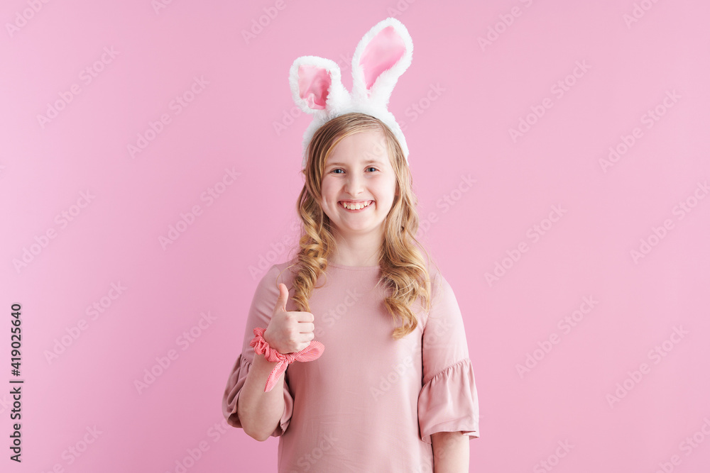 smiling stylish girl in pink dress showing thumbs up on pink