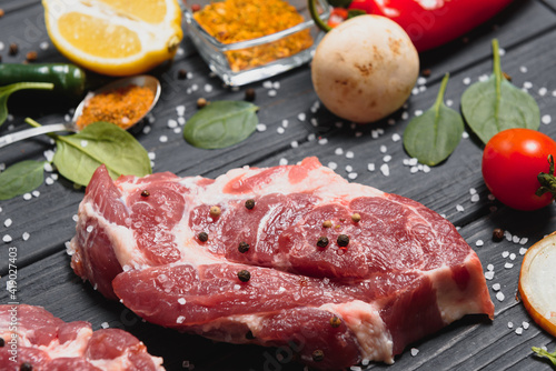 Raw pork meat on wooden cutting board at kitchen table for cooking pork steak roasted or grilled with ingredients herb and spices , Fresh pork