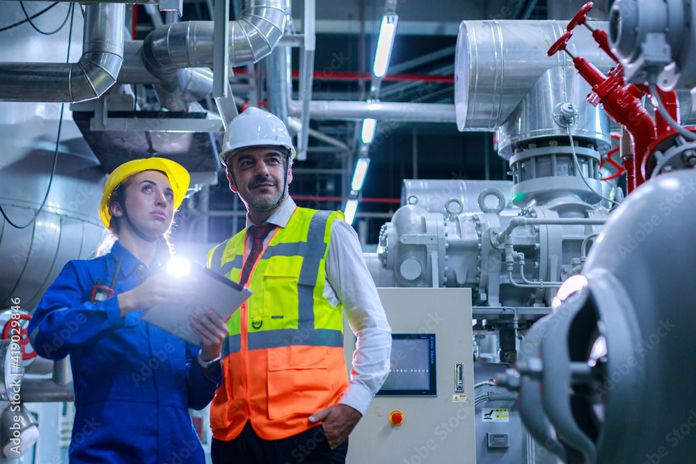 Engineer protective clothing in factory young electrical engineer woman using touchpad with digital tablet and standing and talking in control room factory Engineer protective clothing in factory young electrical engineer woman using touchpad with digital tablet and standing and talking in control room factory