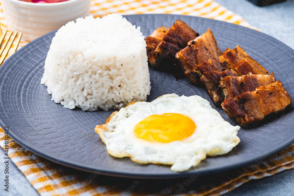 Porksilog (profile shot) -is a famous Filipino meal that consists of fried rice, egg and fried pork slices. Porksilog (profile shot) -is a famous Filipino meal that consists of fried rice, egg and fried pork slices.