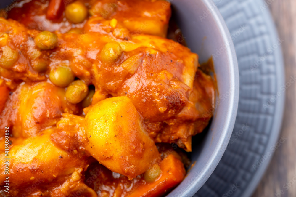 Chicken Afritada (Super Close Up) (Spanish-style Chicken Stew) is a well-known Filipino dish that is cooked in tomato sauce with carrots, potatoes, green peas and bell peppers as the main vegetables.