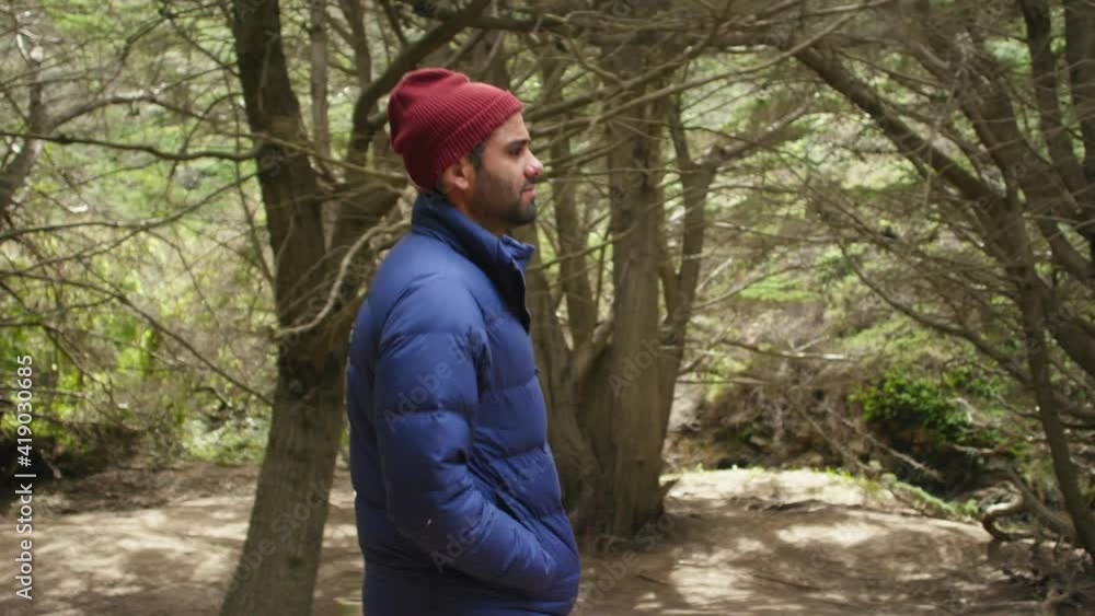 Side profile of a man walking in the forest wearing a blue jacket and beanie. Side profile of a man walking in the forest wearing a blue jacket and beanie.