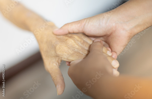 Female hand holding with her father for supporting senior old man in her house, while her father is patient and waiting for recover their health.