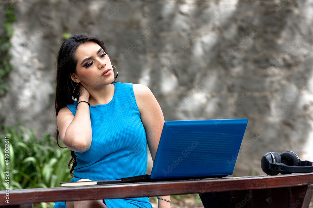 Young frustrated and sore woman with laptop on wooden table sitting in park, outdoor office work concept, with space for text, businesswoman tired and in bad mood Young frustrated and sore woman with laptop on wooden table sitting in park, outdoor office work concept, with space for text, businesswoman tired and in bad mood
