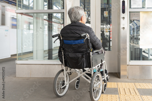 電車のプラットフォームにあるエレベーターに乗る車椅子の高齢者1