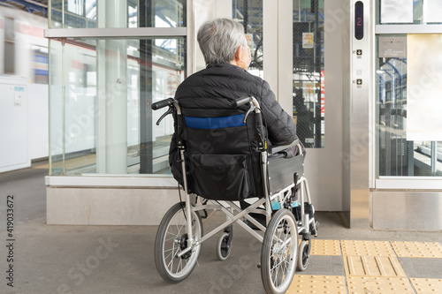 電車のプラットフォームにあるエレベーターに乗る車椅子の高齢者1 photo