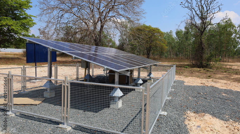 Solar panels and fences. Clean energy panel for electricity generation with metal fence anti-theft in rural area on green plant background with copy space. Selective focus Solar panels and fences. Clean energy panel for electricity generation with metal fence anti-theft in rural area on green plant background with copy space. Selective focus
