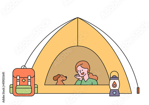 A woman is camping with her dog. The woman and the dog are resting in the tent. flat design style minimal vector illustration.