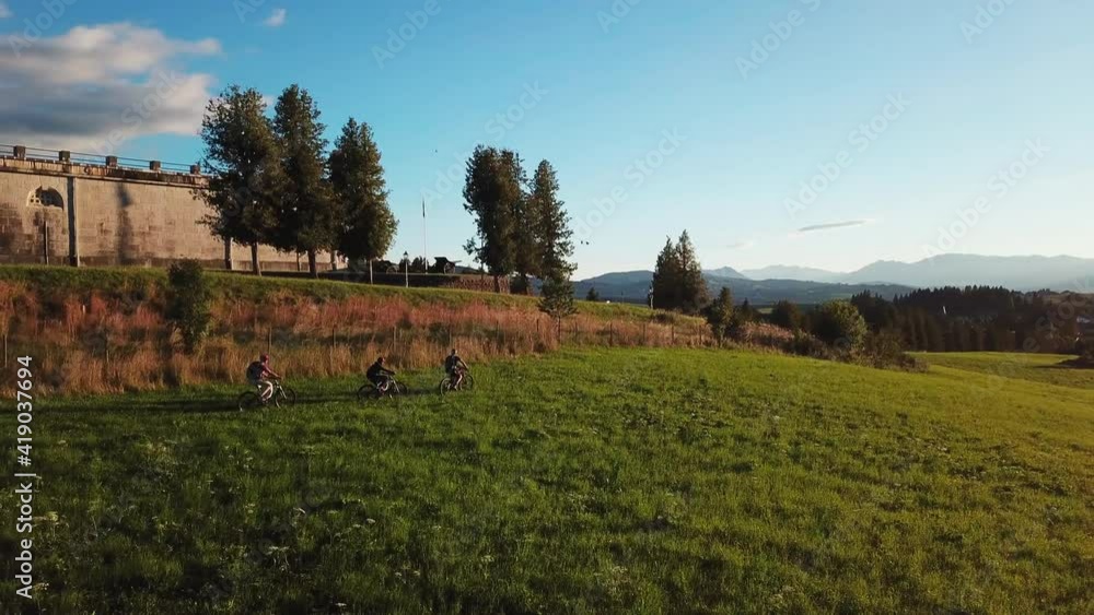 Orbiting view of tourists on bicycles exploring monument building at the hill top. Group of friends on bicycles mountain biking in Italian hills Orbiting view of tourists on bicycles exploring monument building at the hill top. Group of friends on bicycles mountain biking in Italian hills