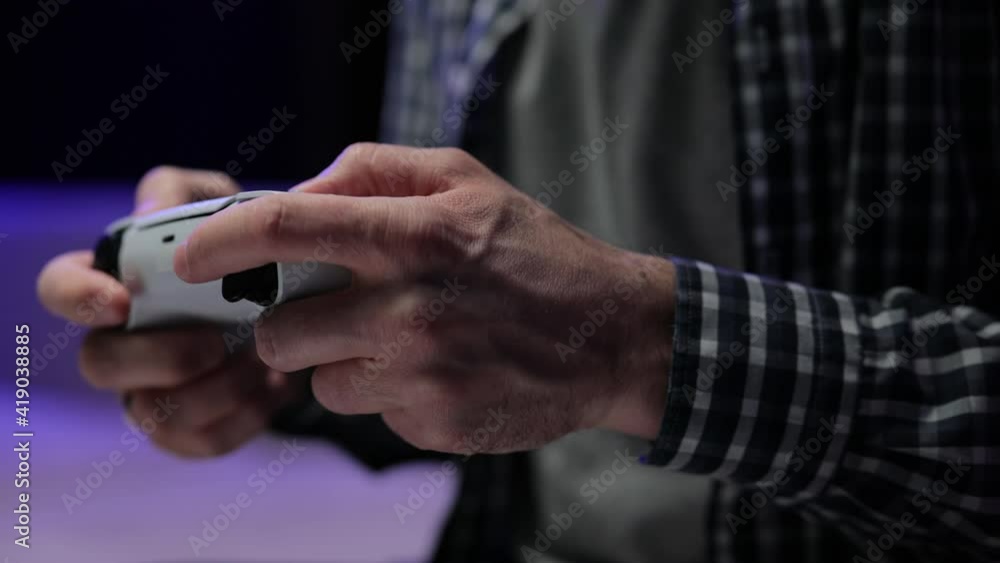 Males hands holding joystick, playing video game and having fun. Close-up of the man holding a white joystick next gen console and playing a video game on TV Males hands holding joystick, playing video game and having fun. Close-up of the man holding a white joystick next gen console and playing a video game on TV