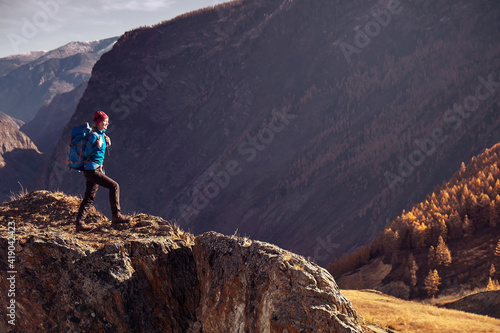 Hiker woman with backpack on rock of a mountain and enjoying sunrise. Travel Lifestyle success concept adventure active vacations outdoor mountaineering sport
