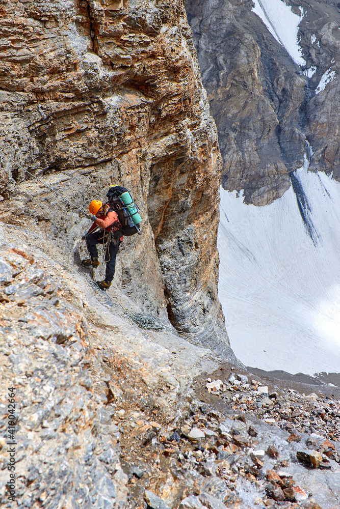 climber with equipment on the slopes climbs on ropes