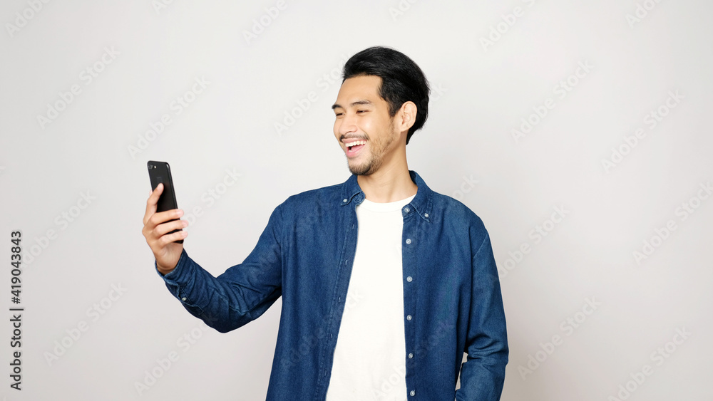 Video call conference, Happy asian man having a video chat on mobile phone  while standing on grey background, Asia male talking video call on a  smartphone, Social distancing foto de Stock