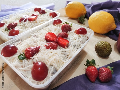 Fruit salad with cheese in plastic container. Multi-colored ripe fruits. lemon  apple  lychee  strawberry and grape.  