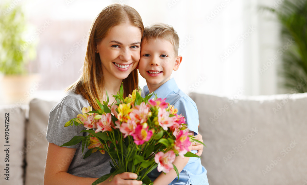 Boy hugging mother with bunch of flowers