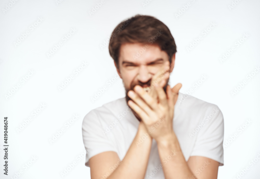 Emotional man with a beard holds his hands near his face on a light background cropped view Emotional man with a beard holds his hands near his face on a light background cropped view