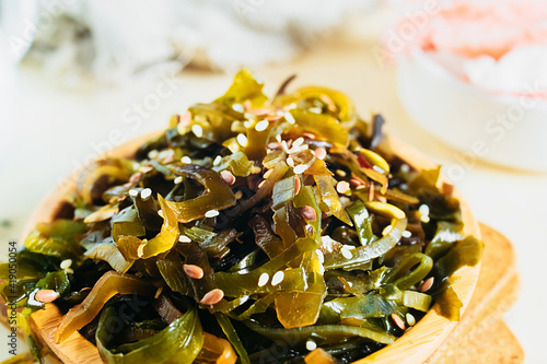 traditional asian dish seaweed salad with sesame seeds on round bamboo plate on table, close up, selective focus photo