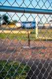 Focus on chain link fence with t-ball background