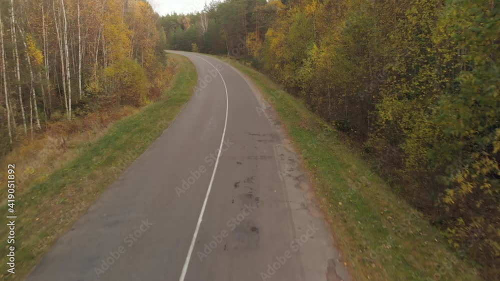 Empty suburban two-lane road in a rural wooded area in the fall. Wide-angle forward movement along Empty suburban two-lane road in a rural wooded area in the fall. Wide-angle forward movement along