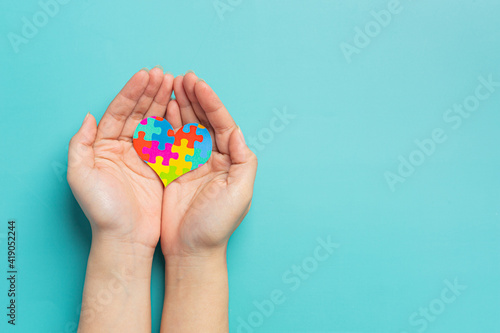 child hands holding jigsaw puzzle heart shape, Autism Day