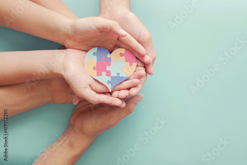 Adult and chiildren hands holding jigsaw puzzle heart shape, Autism awareness,Autism spectrum disorder family support concept, World Autism Awareness Day