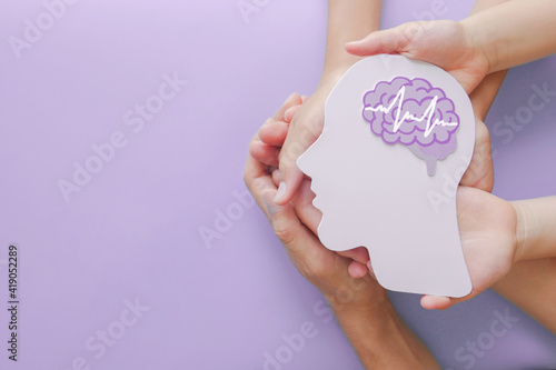 Adult and child hands holding encephalography brain paper cutout,autism, Stroke, Epilepsy and alzheimer awareness, seizure disorder, stroke, ADHD, world mental health day concept photo