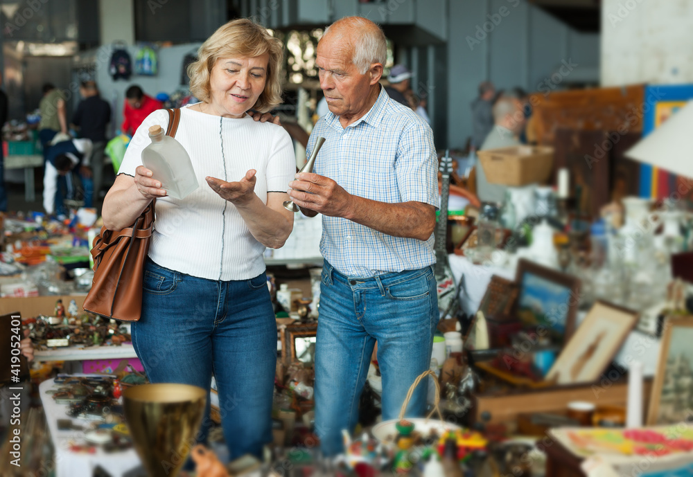 Elderly couple in flea market chooses antique items. High quality photo