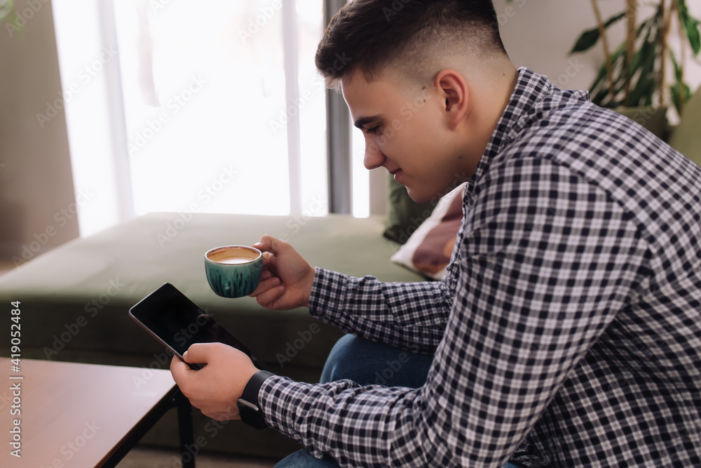 Smiling man reading smartphone, black screen and coffee cup. Blurred background Smiling man reading smartphone, black screen and coffee cup. Blurred background