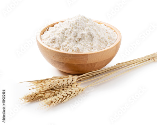 Ears of wheat and flour in a wooden bowl on a white background