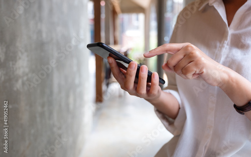 Closeup image of a woman holding and using mobile phone