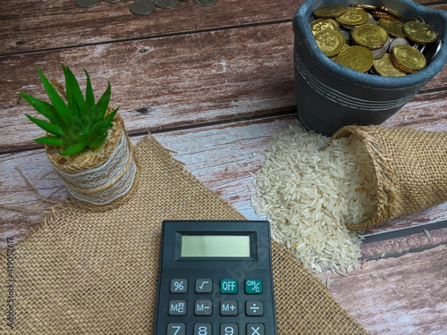 Raw rice, calculator and coin over wooden background for zakat concept photo