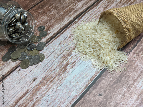 Raw rice and coin over wooden background for zakat concept photo