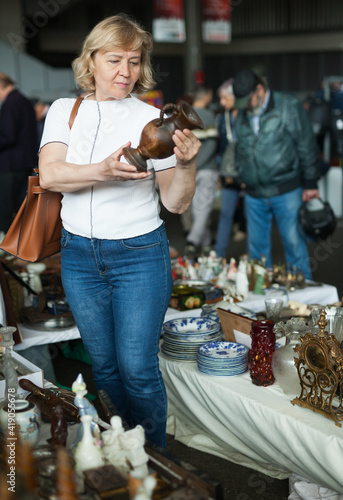 Mature woman buys handmade ceramic vase at flea market. High quality photo