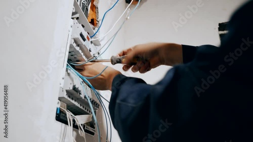 An electrician assembles an electrical panel in an apartment. Electrical box contains many terminals, relays, wires and switches. Manufacture and installation concept concept.
