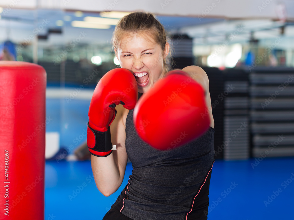 Portrait of young positive woman boxer training in fitness center