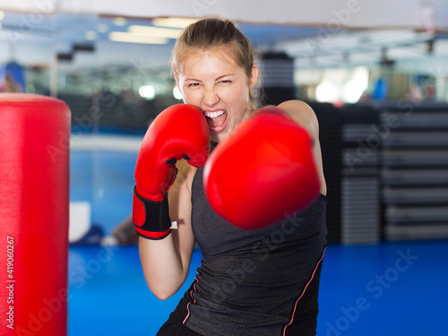 Portrait of young positive woman boxer training in fitness center © JackF
