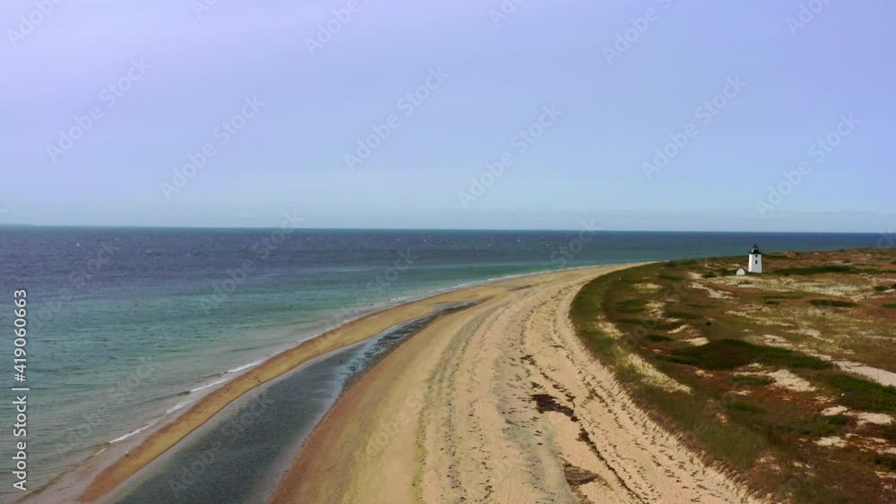 Aerial shot of lighthouse at beach against blue sky on sunny day, drone flying forward over coastline - Cape Cod, Massachusetts Aerial shot of lighthouse at beach against blue sky on sunny day, drone flying forward over coastline - Cape Cod, Massachusetts