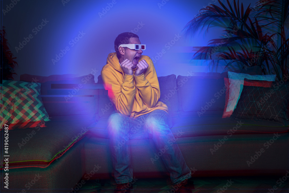 Fototapeta premium Man watching a 3D movie at home with retro 3D glasses