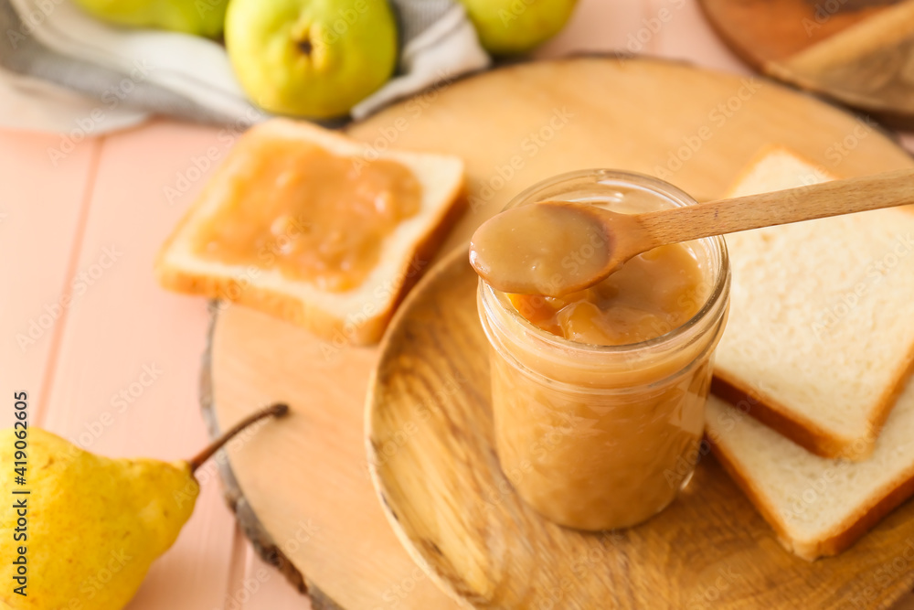 Jar of tasty pear jam with bread on wooden table Jar of tasty pear jam with bread on wooden table